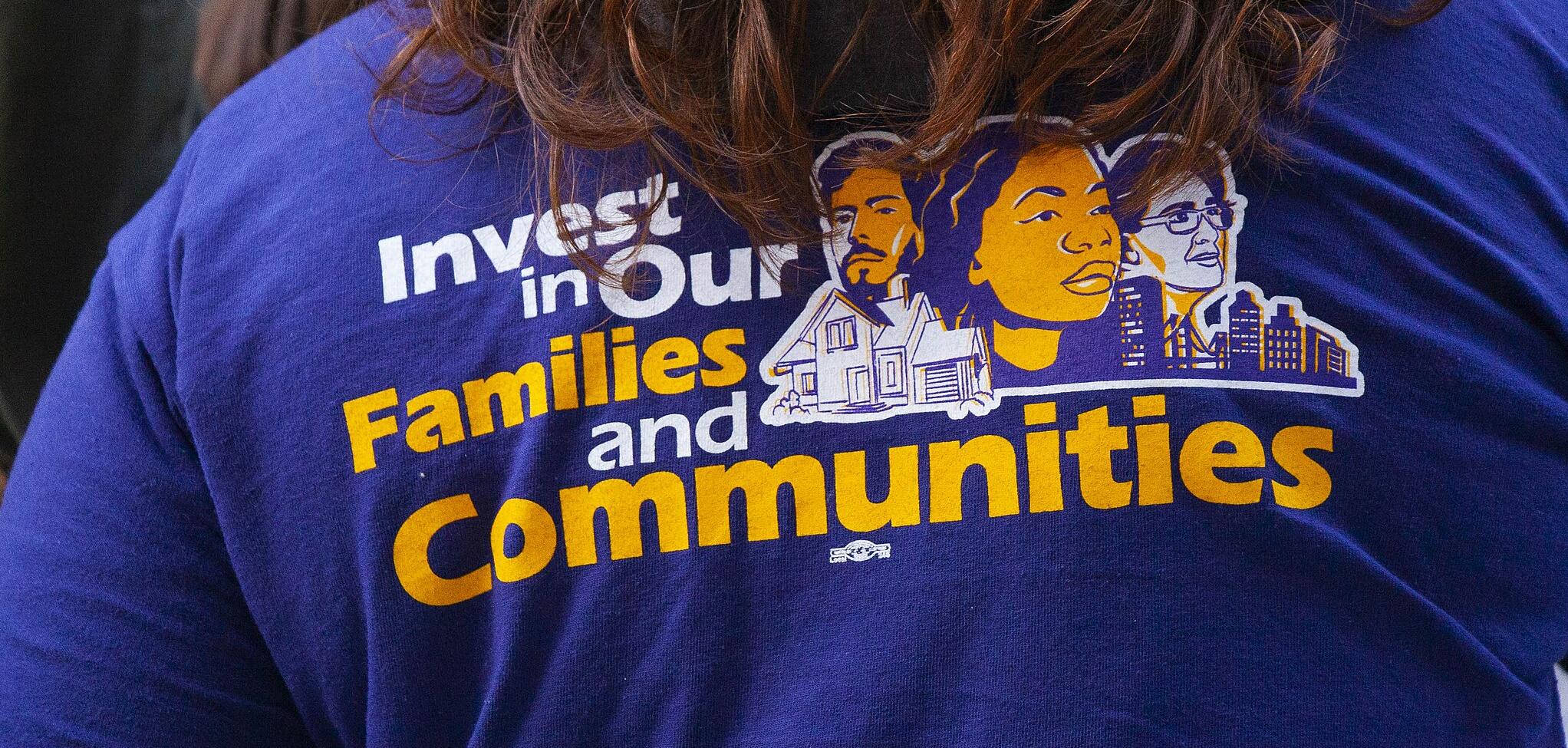 A T-shirt that reads "Invest in our families and communities"