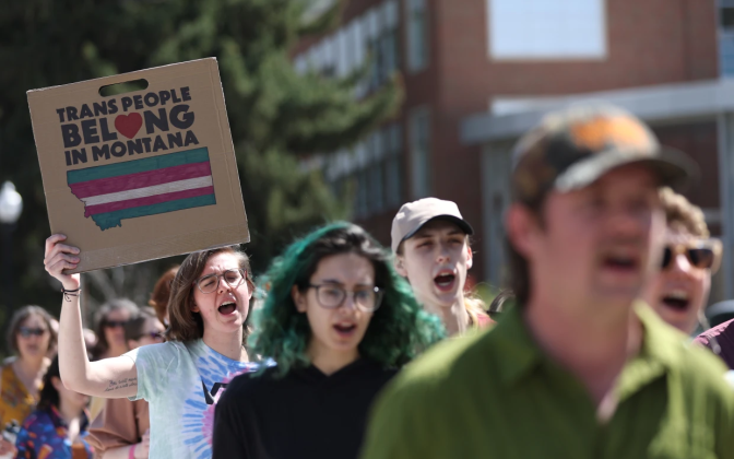protesters holding a sign saying "Trans people belong in Montana"