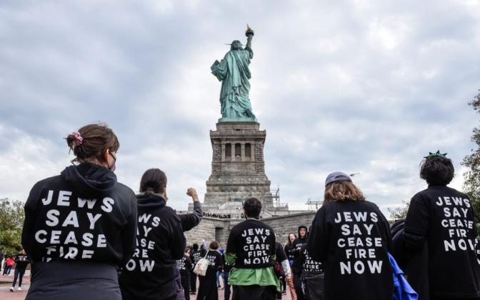 Statue of Liberty with people wearing hoodies saying "Jews Say Cease Fire"