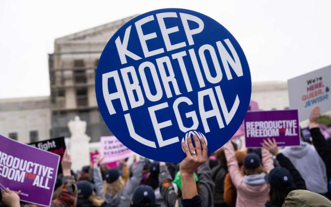 a hand holding a sign that reads "Keep Abortion Legal"